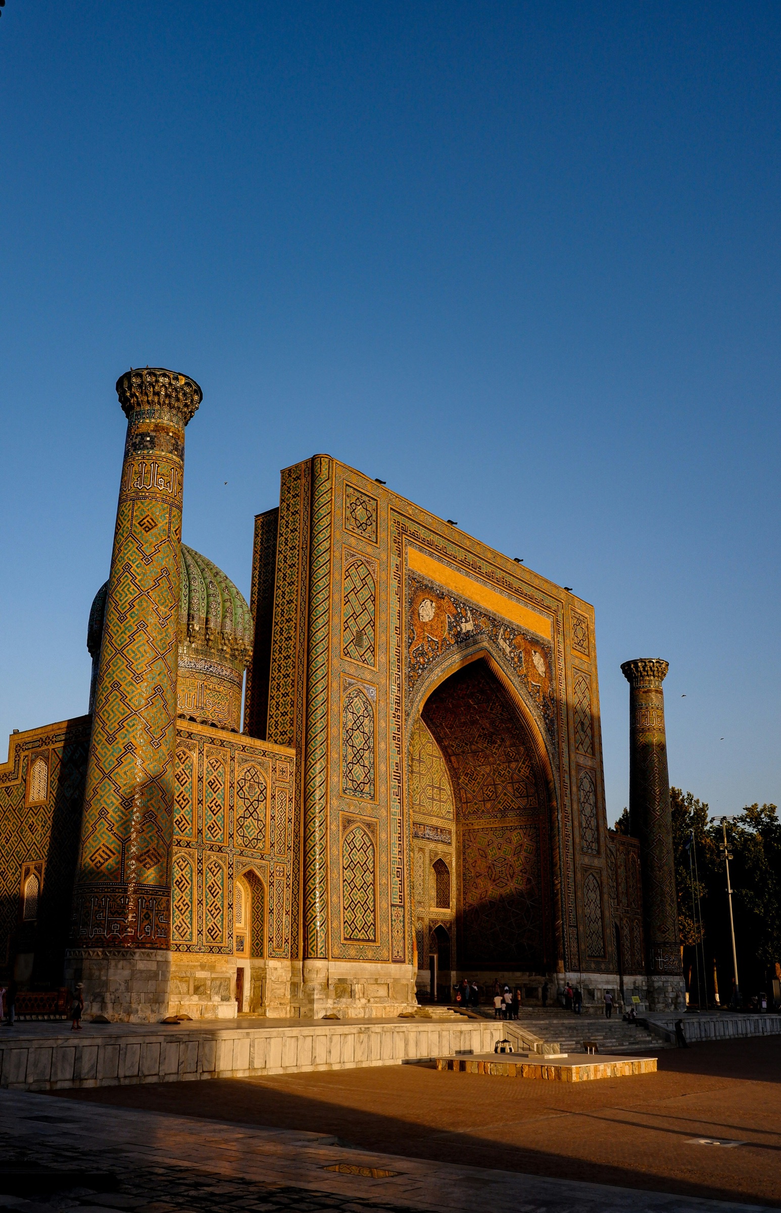 The tiled facade of a Samarkand madrasa at golden hour